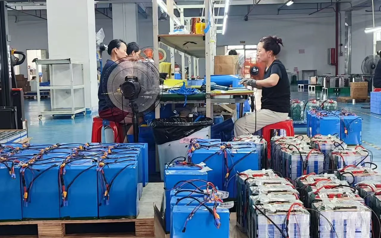 Workshop assembly photograph showing a person working at a bench with battery packs