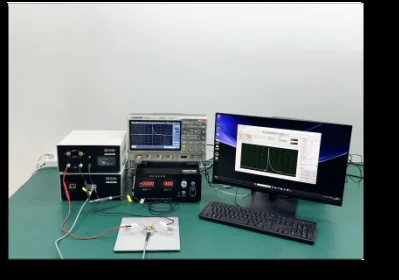 Benchtop electrical instruments, an oscilloscope and a wired sample beside a computer