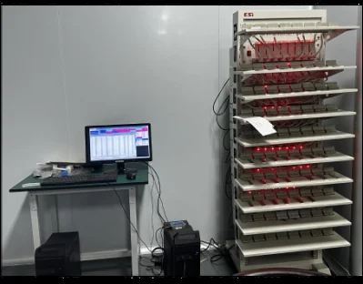 A wired multi-shelf equipment rack beside a computer workstation