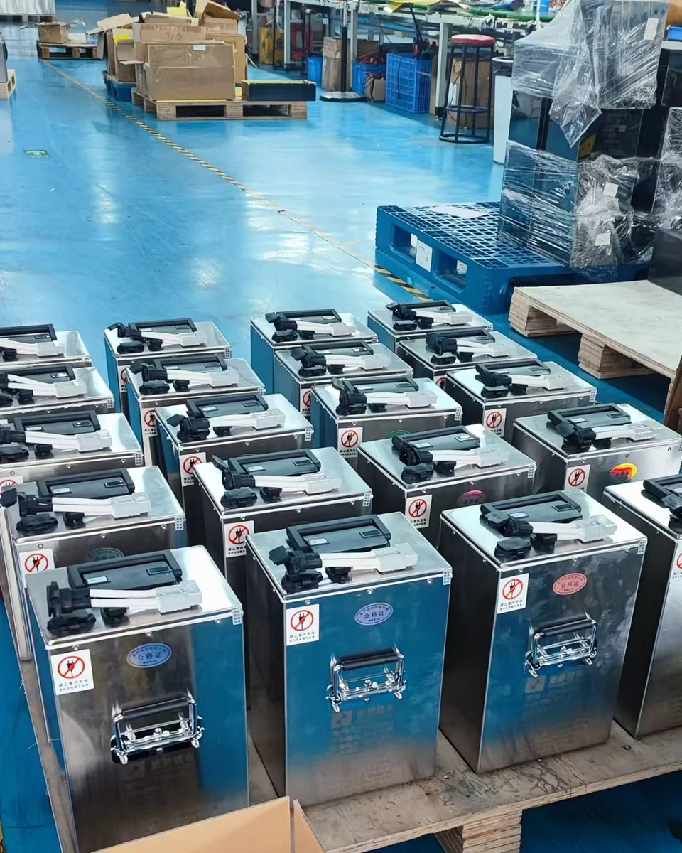 Battery enclosures staged on pallets near cartons and wrapped items in a workshop